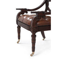 Armchair leg detail with ornate carvings and casters.