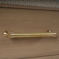 Close-up of the gold handle on wooden dresser.