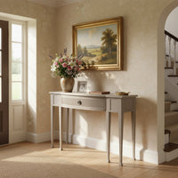 Console table styled in entryway with flowers and frame.