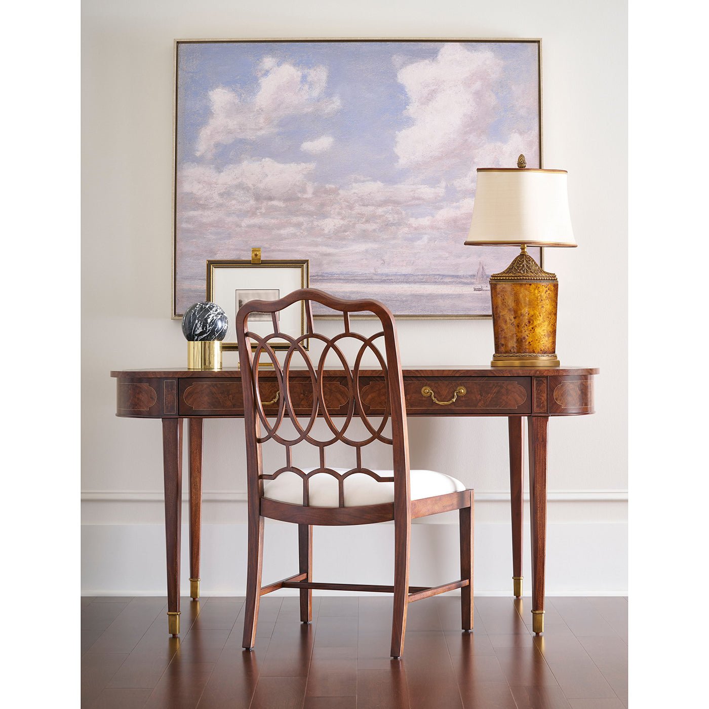 Writing table with decorative items, chair, and lamp setup.