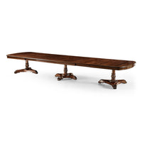 Extended mahogany dining table displaying intricate pedestal design.