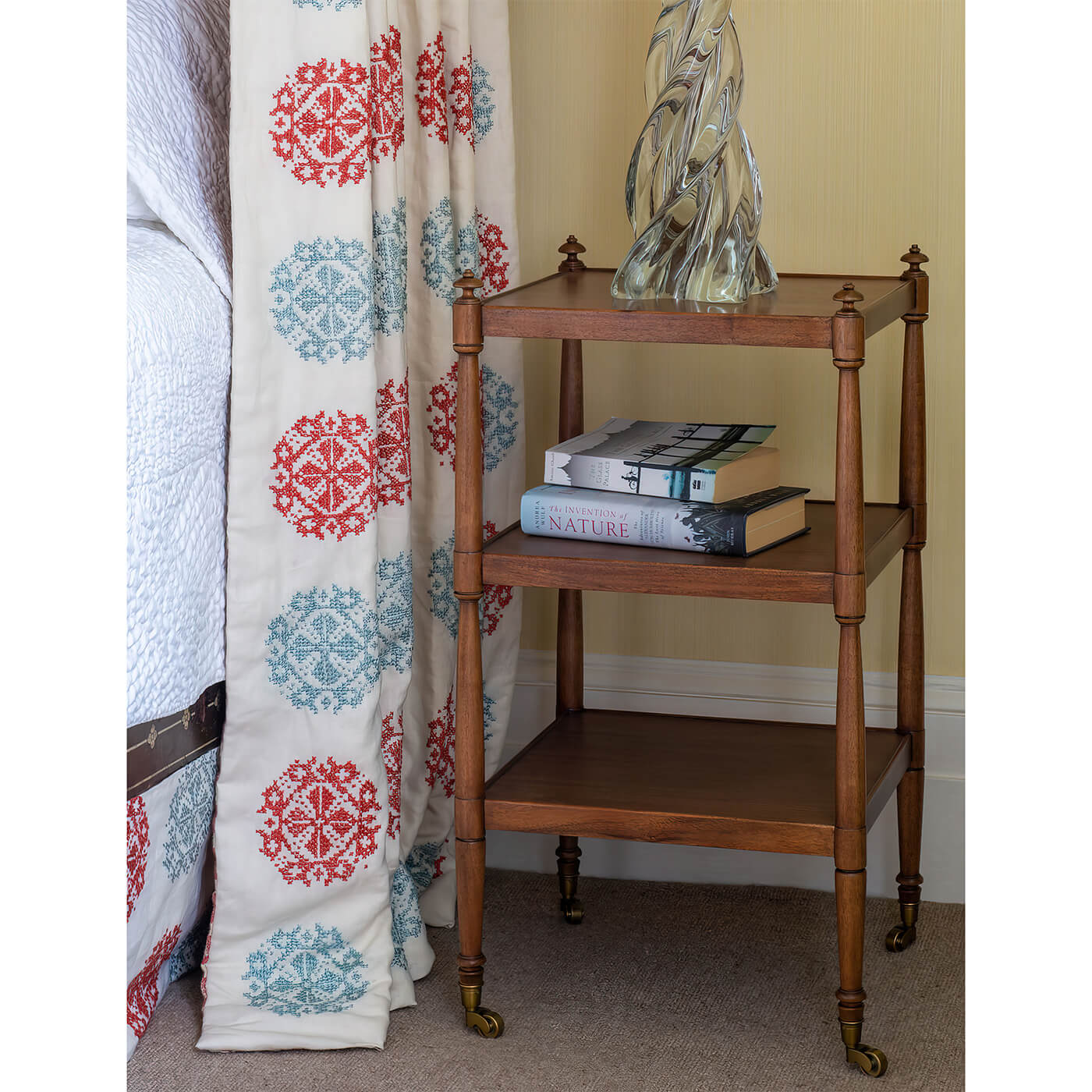 Wooden etagere used as bedside table with books.