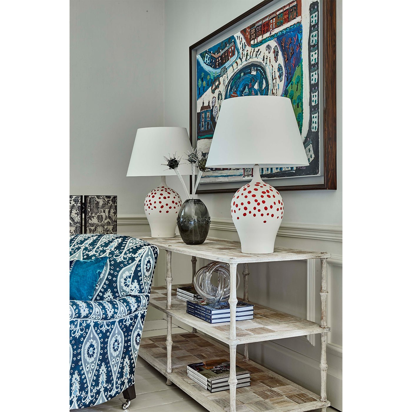 Console table styled with lamps and books in a room.
