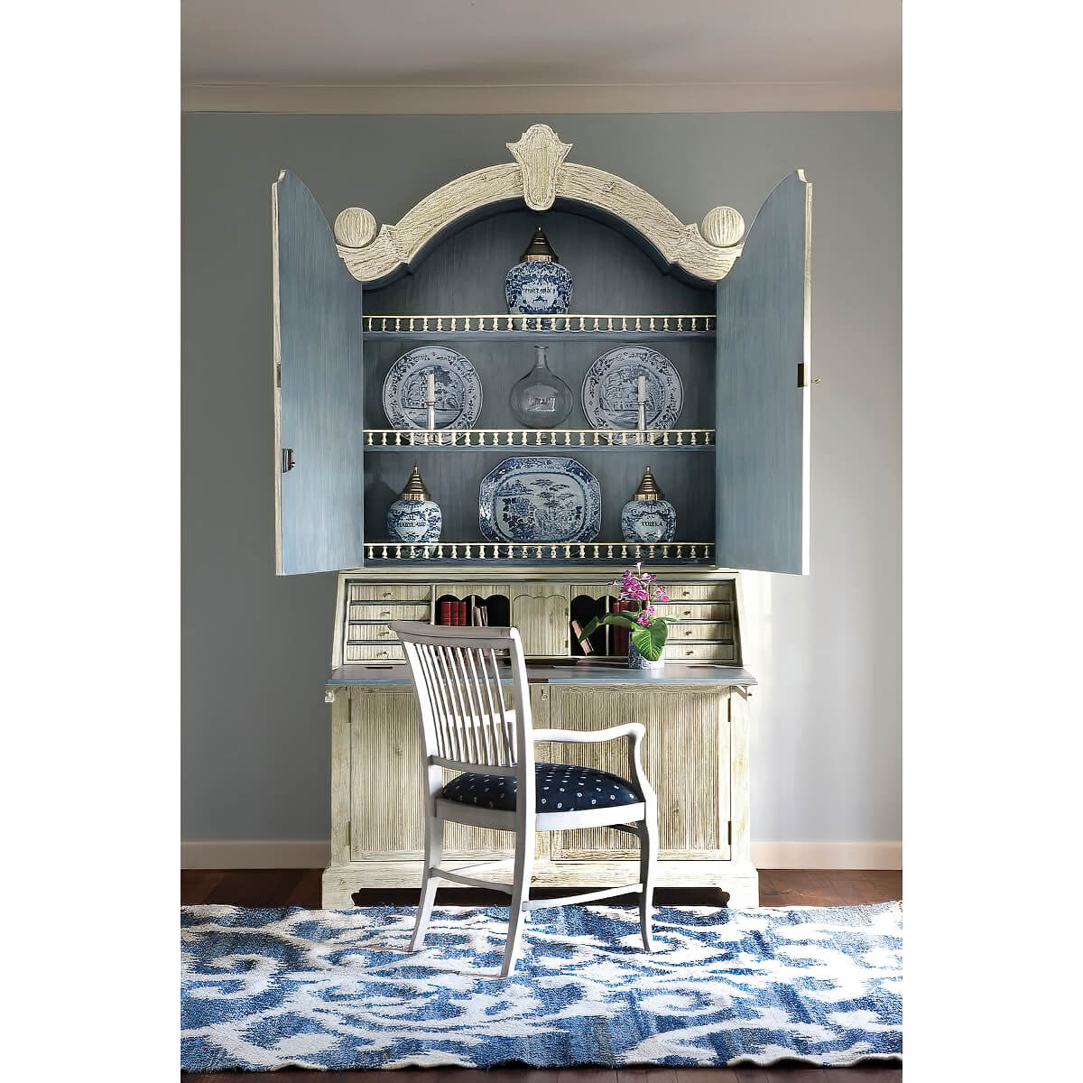Bookcase open styled with decor, chair in front.
