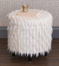 Faux fur ottoman displaying decor items on top.