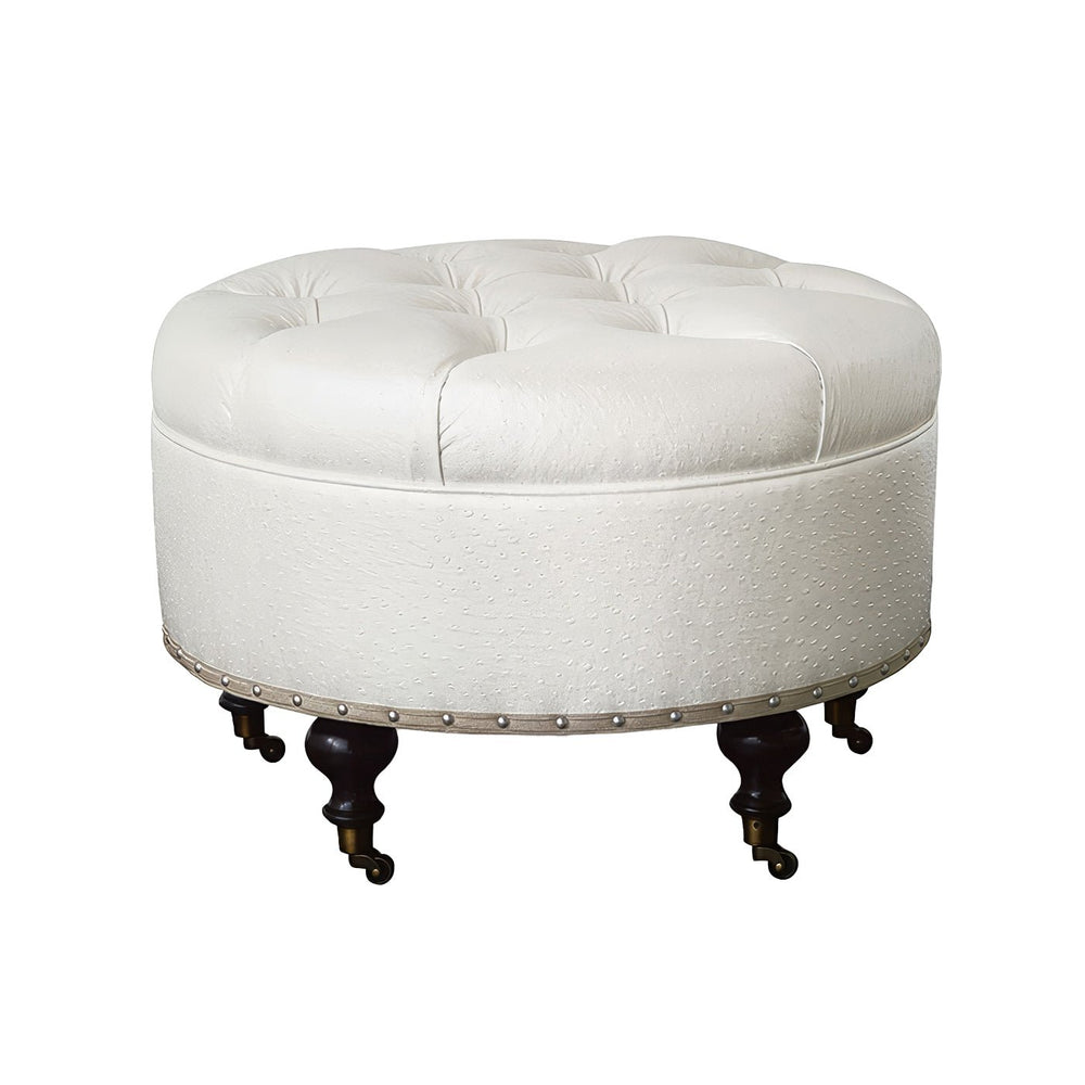 Round white ottoman with dark wooden legs, faux leather texture.