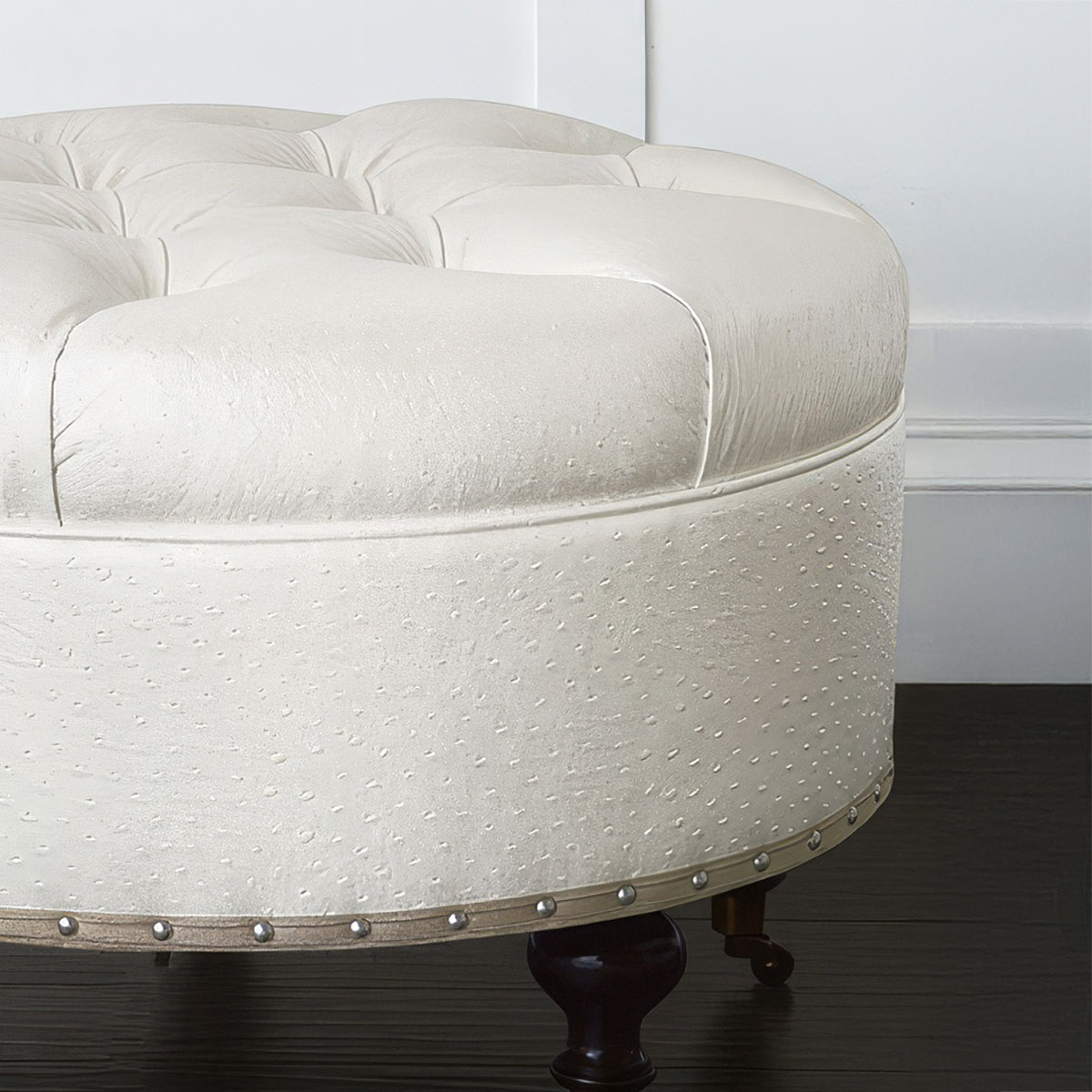Close-up of white ottoman, nailhead trim, faux ostrich leather.