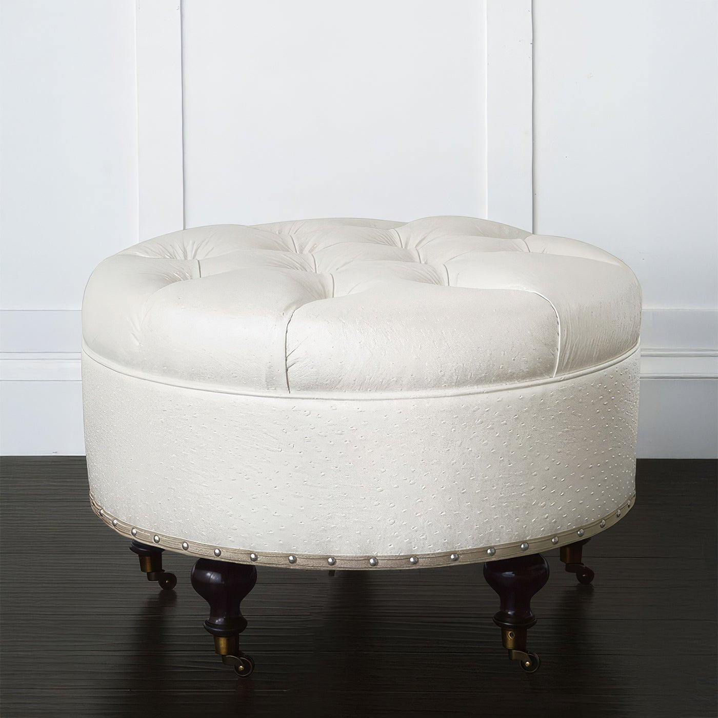 Detailed view of round ottoman, tufted design, white upholstery.
