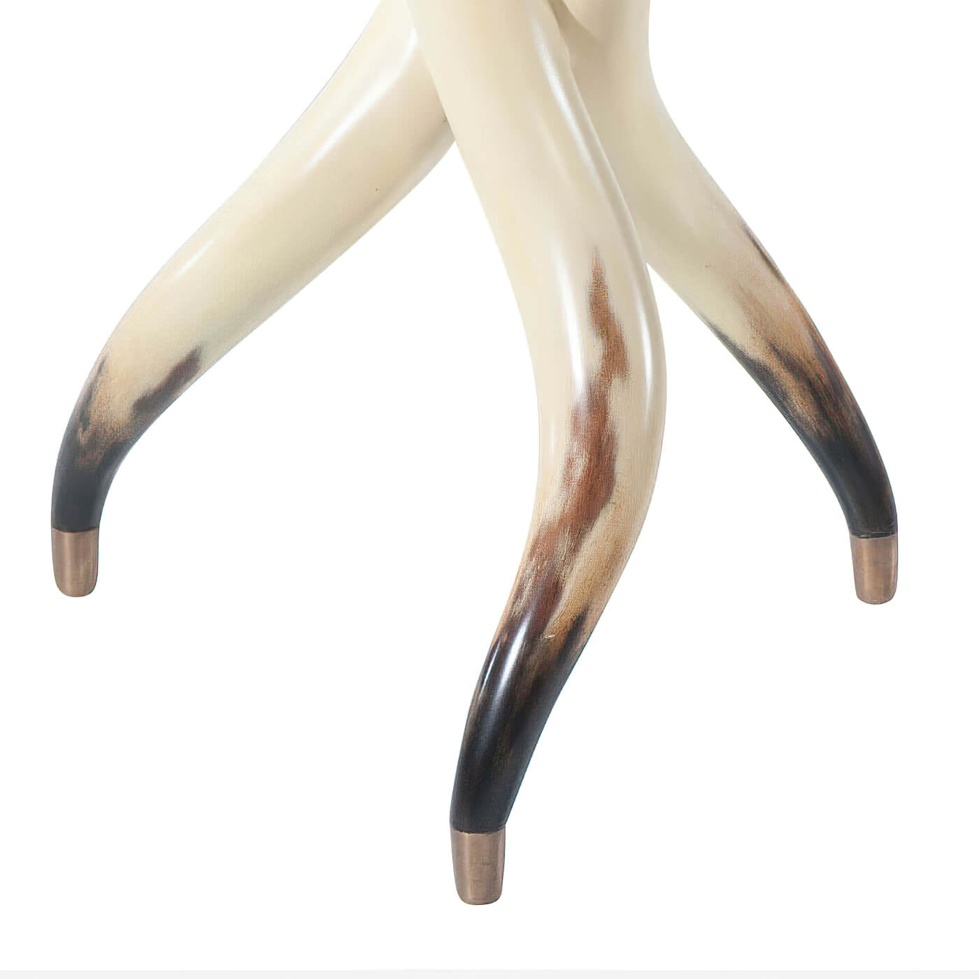 Close-up of table legs resembling steerhorns with brass tips.