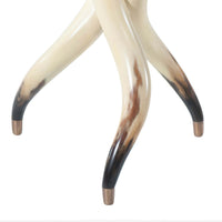 Close-up of table legs resembling steerhorns with brass tips.