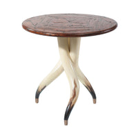 Round steerhorn side table with unique three-legged design.