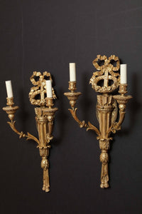 Pair of sconces with decorative ribbons and candles.