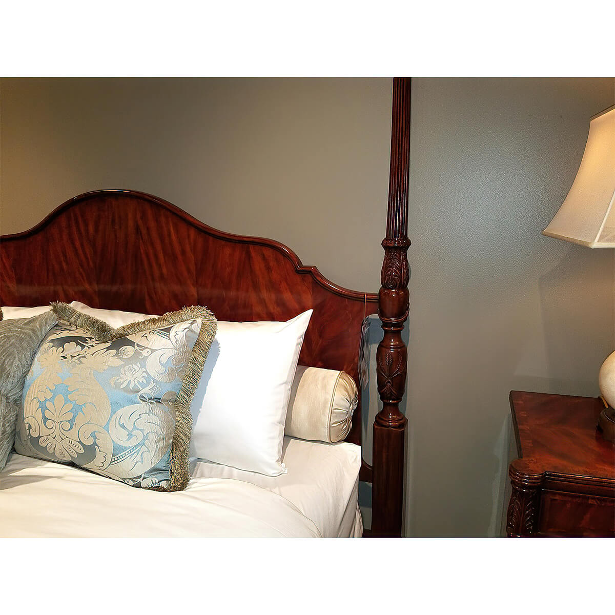 Bedside view of mahogany king size bed with pillows.
