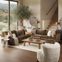 Brown sectional styled with pillows and a throw around a wood coffee table beside tall windows