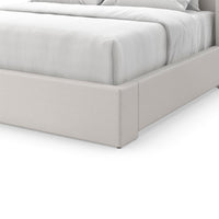 Close-up of upholstered bed base, light fabric detail.