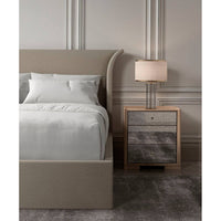 Bed with flared headboard and nightstand with lamp.