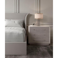 Upholstered bed and gray nightstand with lamp, side view.