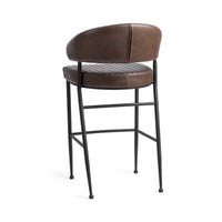 Three-quarter rear view of the fluted brown leather bar stool, showing the smooth curved back and iron footrest