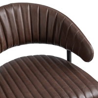 Close-up of the fluted brown leather bar stool’s curved, channel-stitched back and padded seat