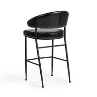 Three-quarter rear view of the fluted black leather bar stool, showing the smooth curved back and black iron frame