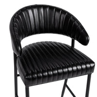 Close-up of the fluted black leather bar stool’s curved back and padded channel-stitched seat