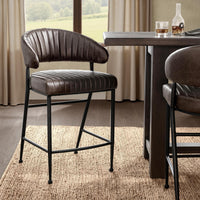 Fluted brown leather counter stool beside a dark wood counter-height table, with a second stool partly visible
