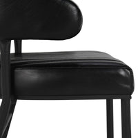 Side detail of the fluted black leather counter stool’s padded seat, curved back and iron supports