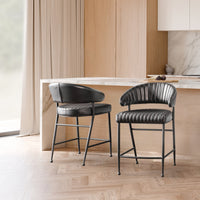Two fluted black leather counter stools beside a light wood kitchen island, shown from front and rear