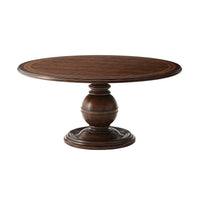 Round wooden dining table with decorative pedestal base.