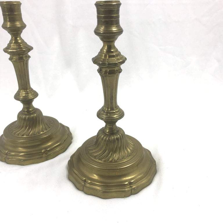Two French bronze candlesticks, angled view, decorative base visible.
