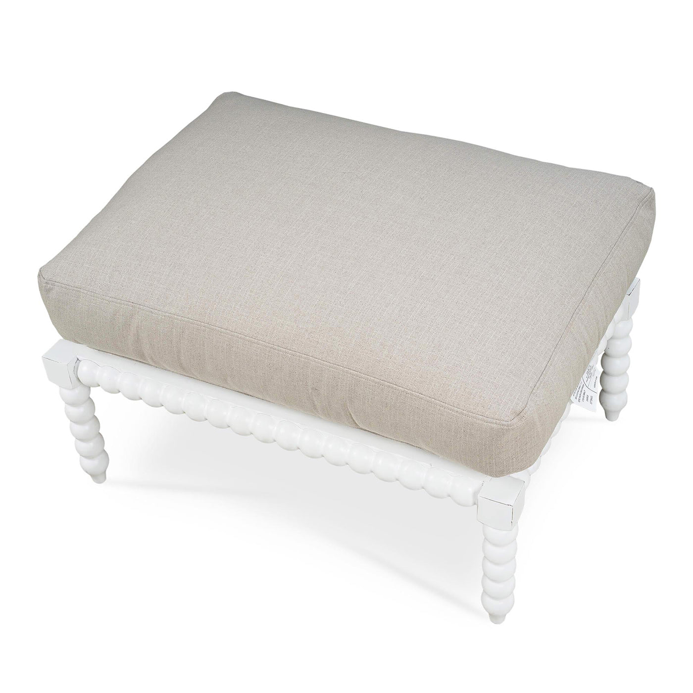 Top view of beige cushion on white bobbin ottoman.