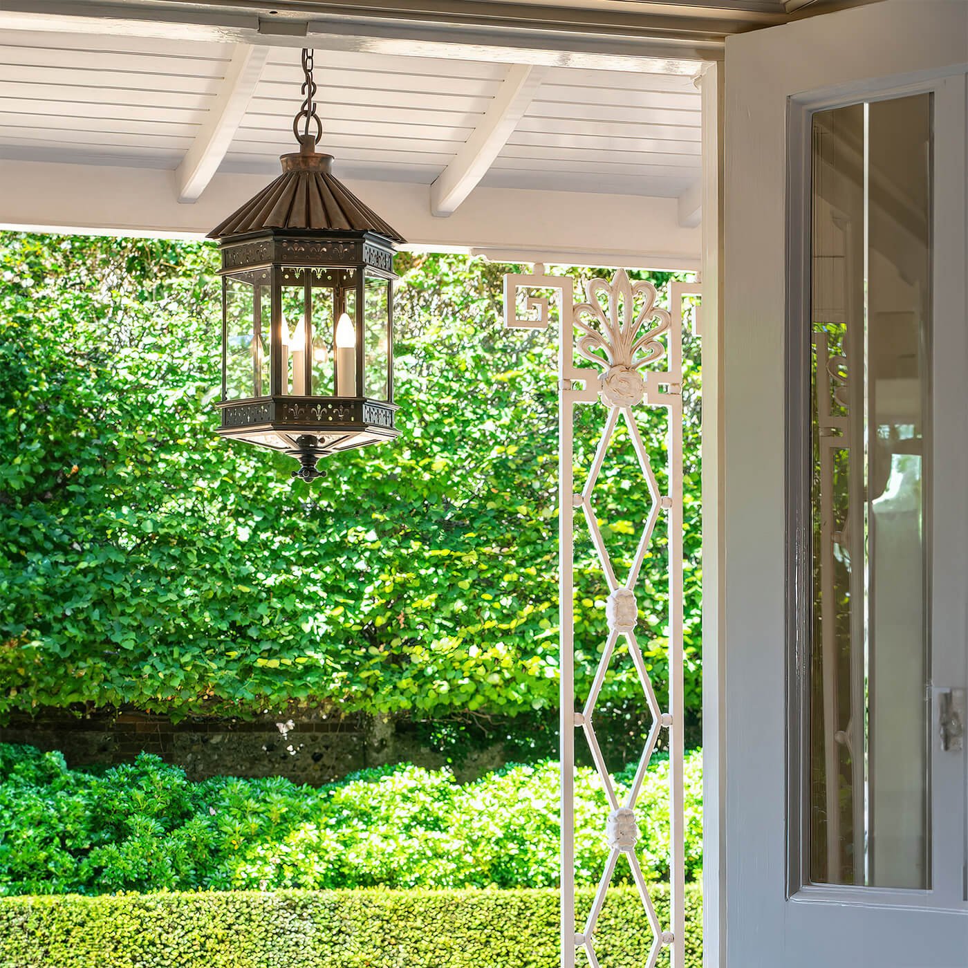 Copper bronze lantern hanging outdoors, garden background view.
