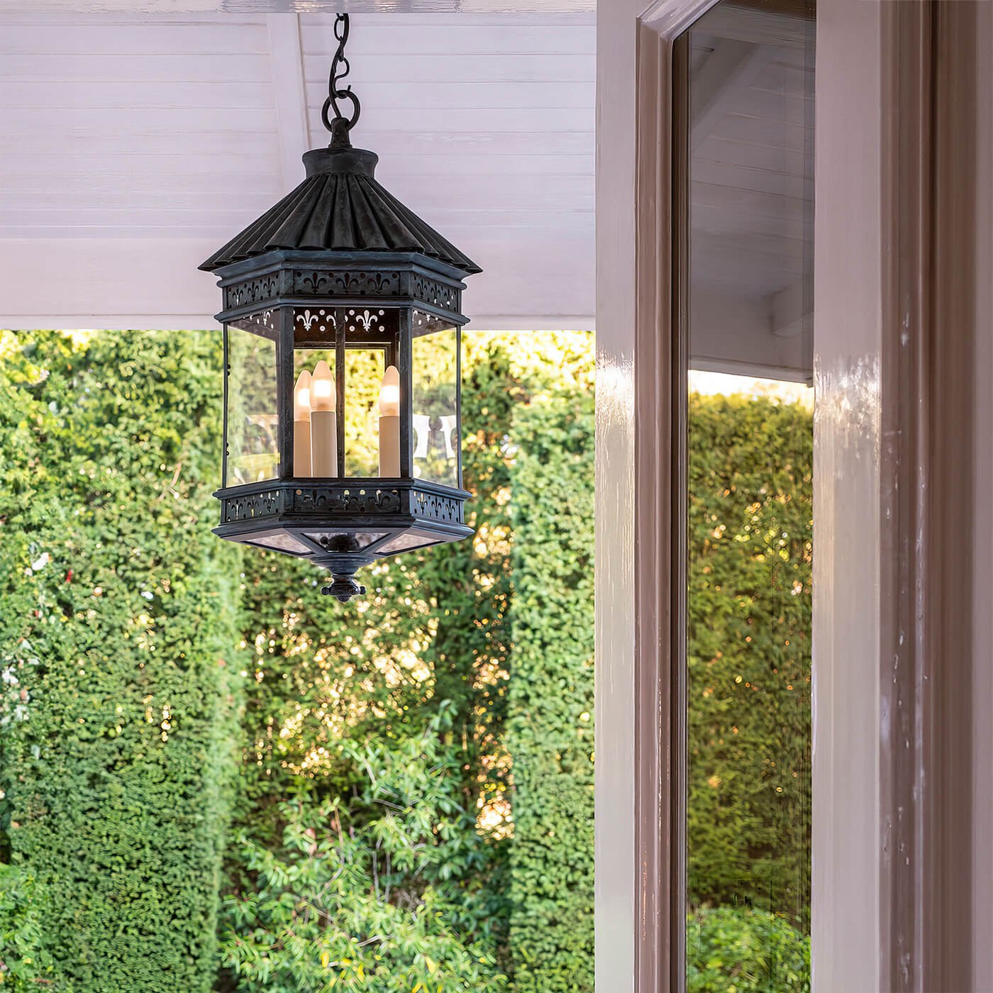 Hanging French country lantern under porch, daytime.