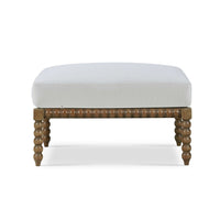 White cushioned ottoman with bobbin legs, front view.