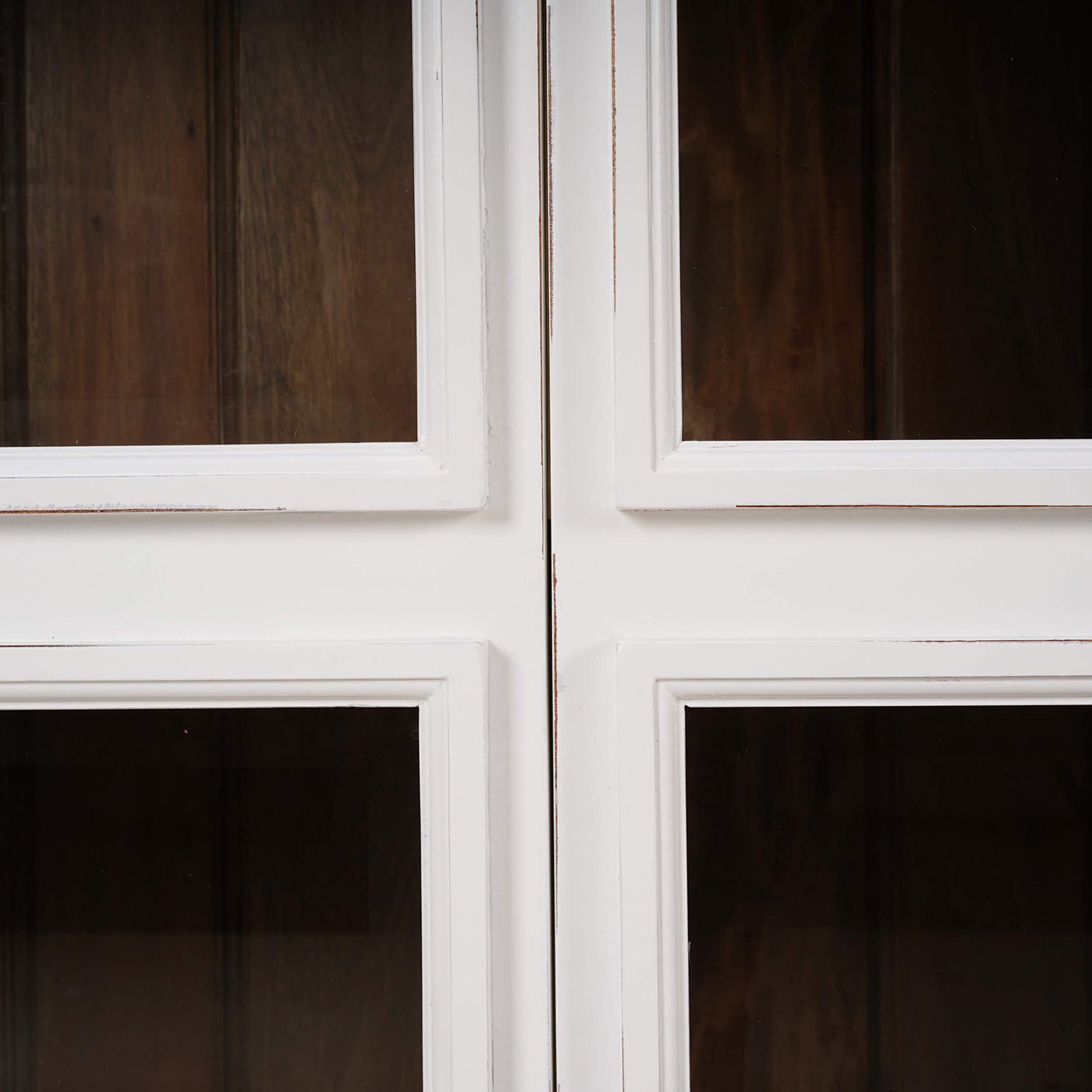 Glass panel and wood texture detail on white credenza.