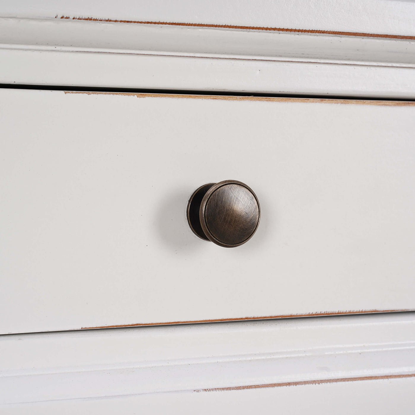 Detailed view of round metal knob on credenza drawer.