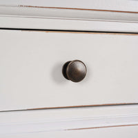 Detailed view of round metal knob on credenza drawer.