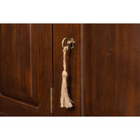 Close-up of door tassel on walnut buffet sideboard.
