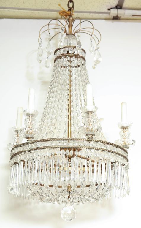Crystal chandelier displayed against white wall, elegant design.