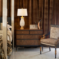 Bedroom setting with French Empire style armchair beside dresser.