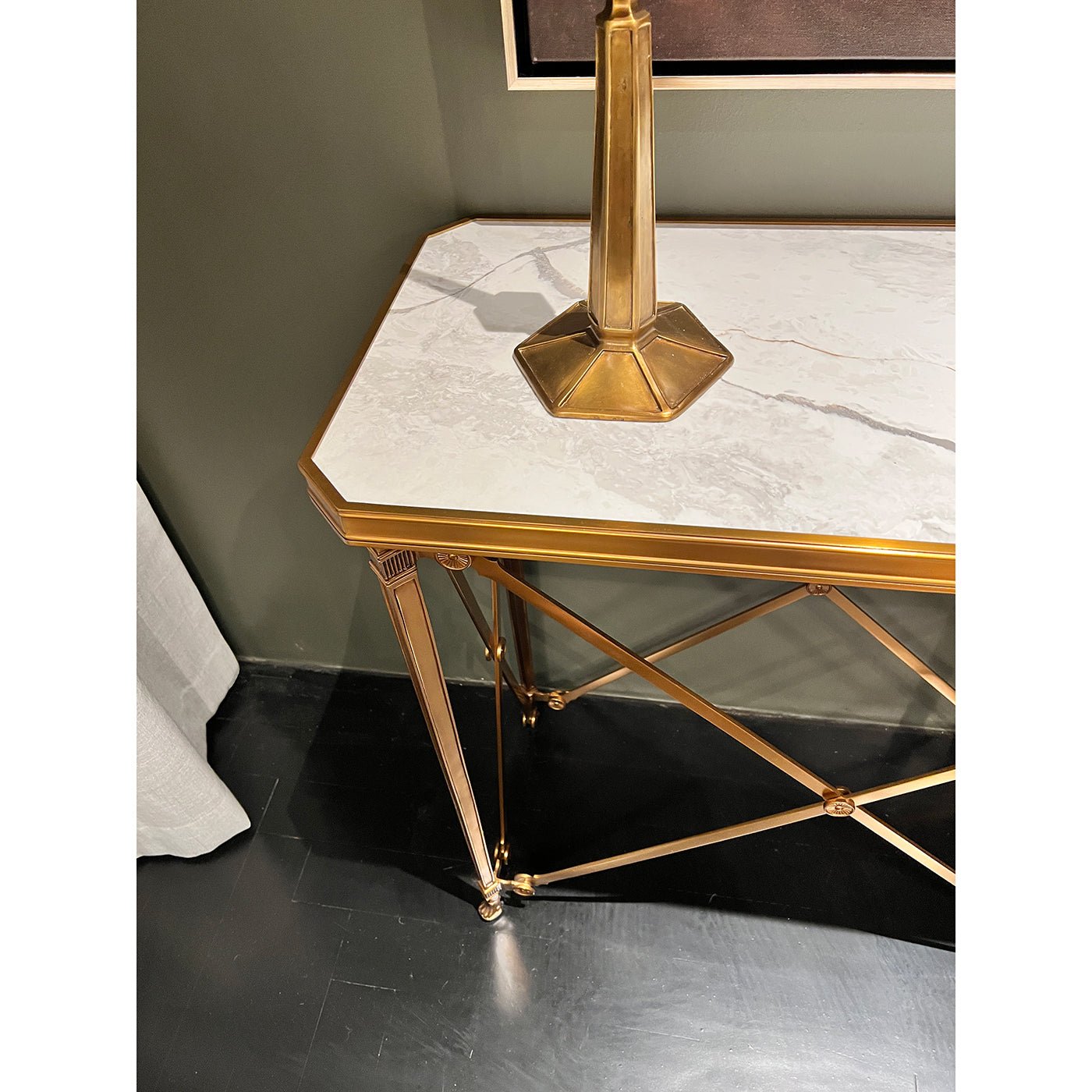 Console table with marble top, gold frame on dark floor.