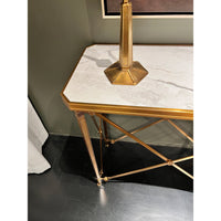 Console table with marble top, gold frame on dark floor.