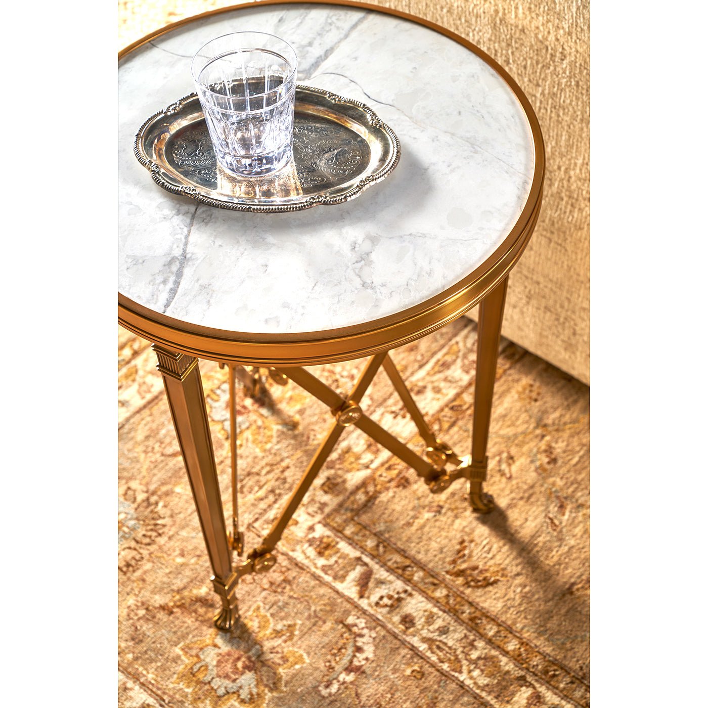 Round accent table with glass and silver tray on top.