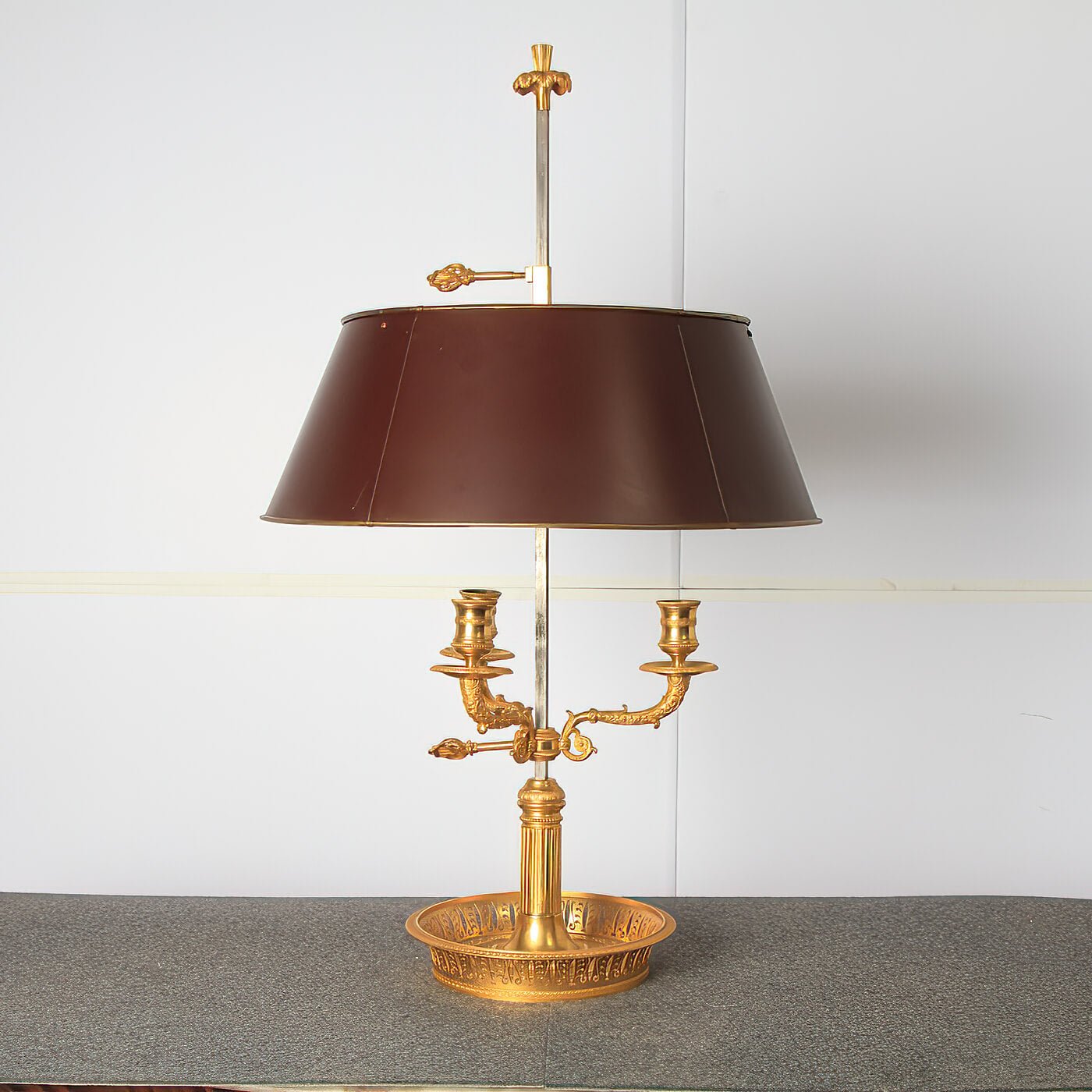 Gold French Louis XVI bouillotte lamp on gray table surface.