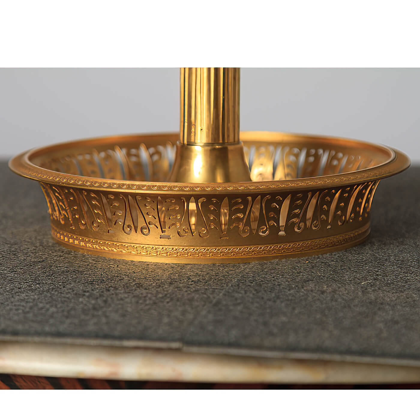 Close-up of intricate design on lamp's gold base.