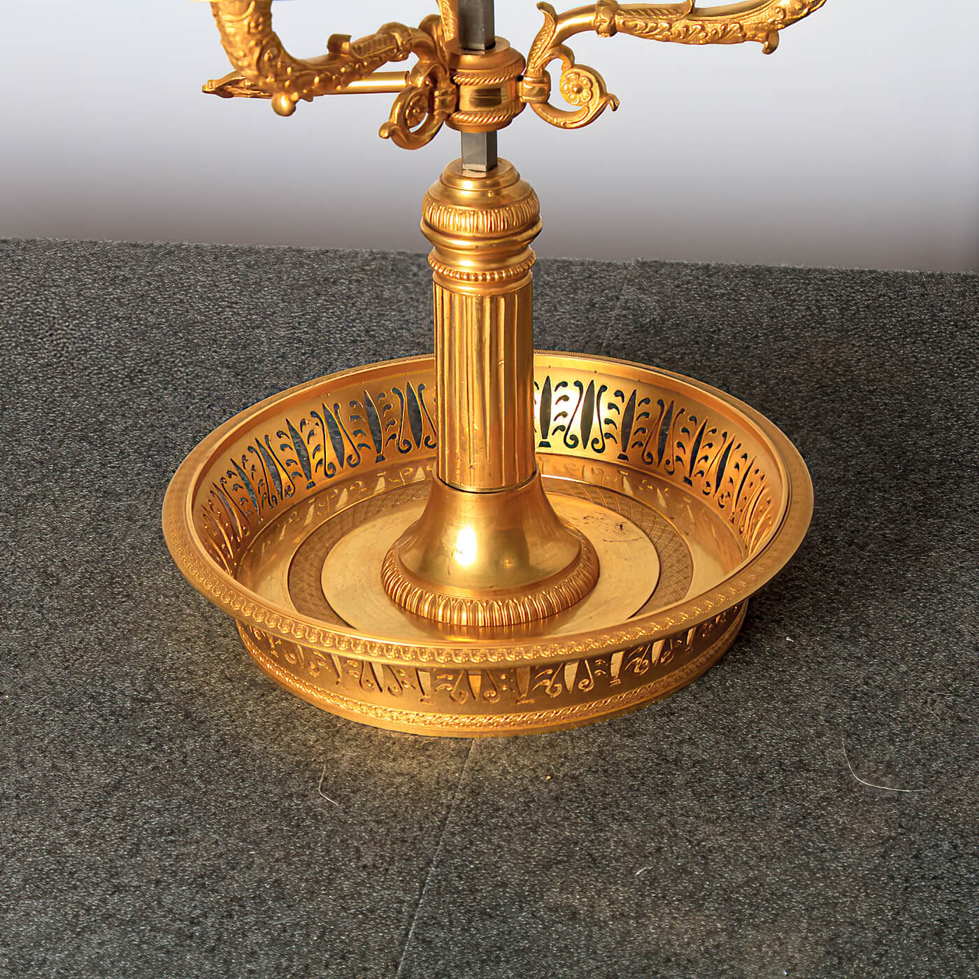 Lamp's ornate gold base on textured table.