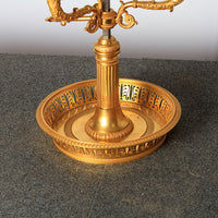 Lamp's ornate gold base on textured table.