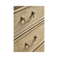 Detailed drawer handles on natural wood commode.