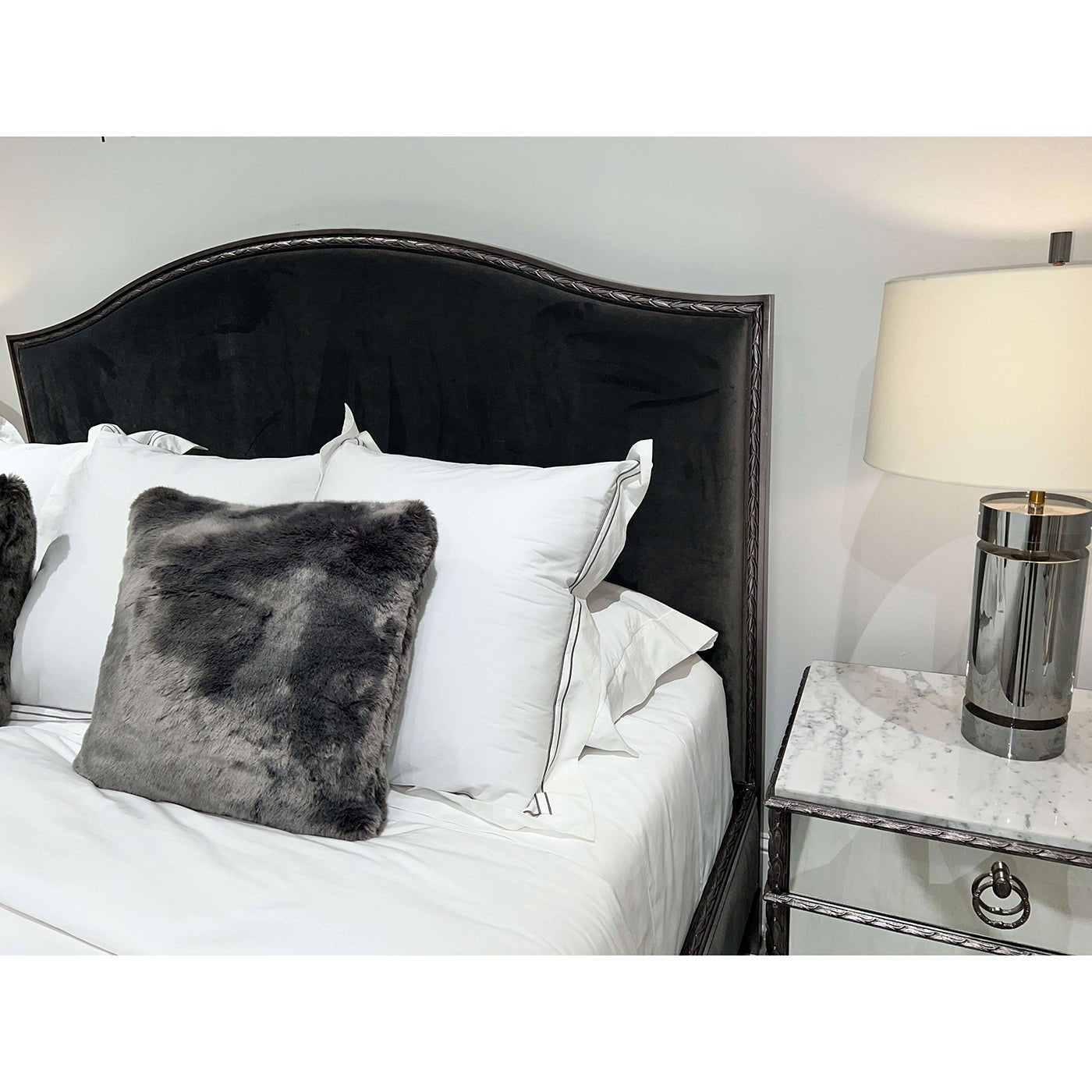 Mirrored nightstand detail next to plush bed and lamp.