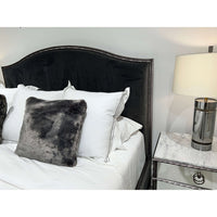 Mirrored nightstand detail next to plush bed and lamp.